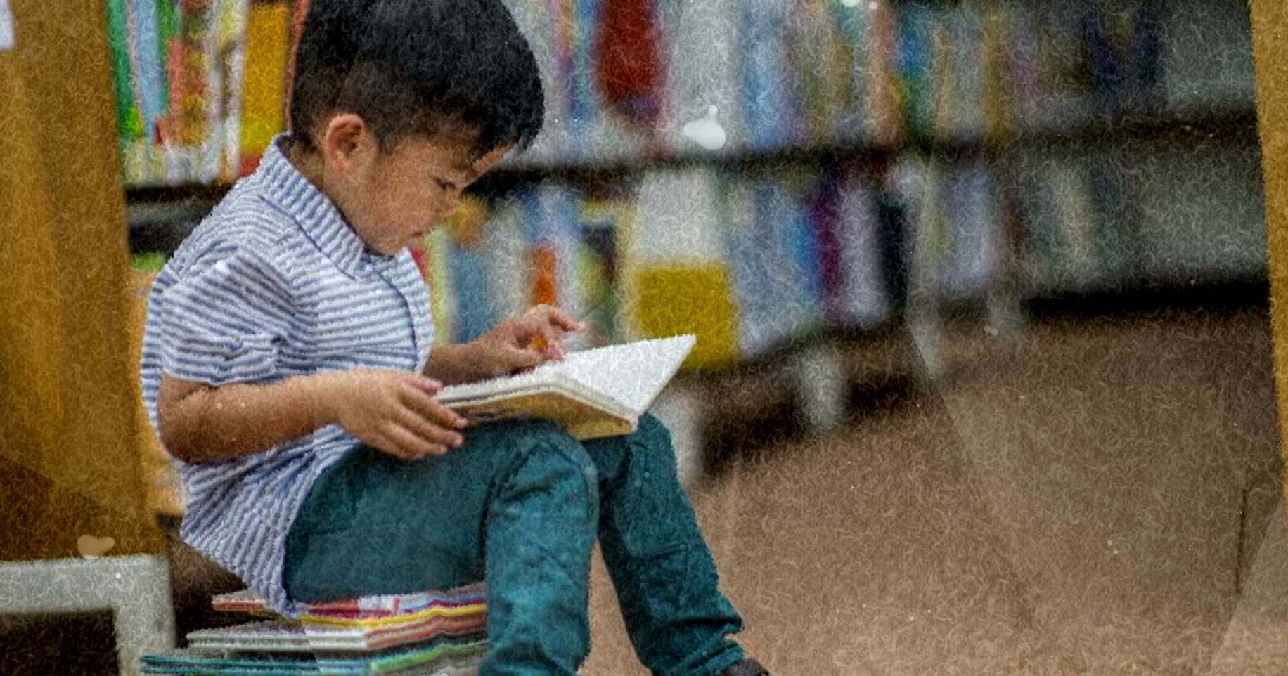 A young child absorbed in a book among library shelves