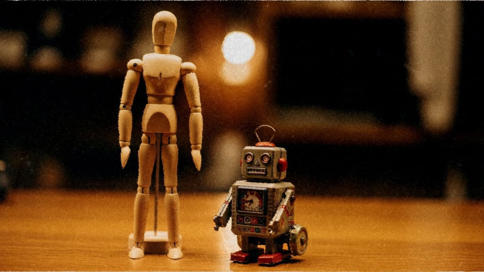 A tailor's wooden mannequin beside a small toy robot on a shop counter.
