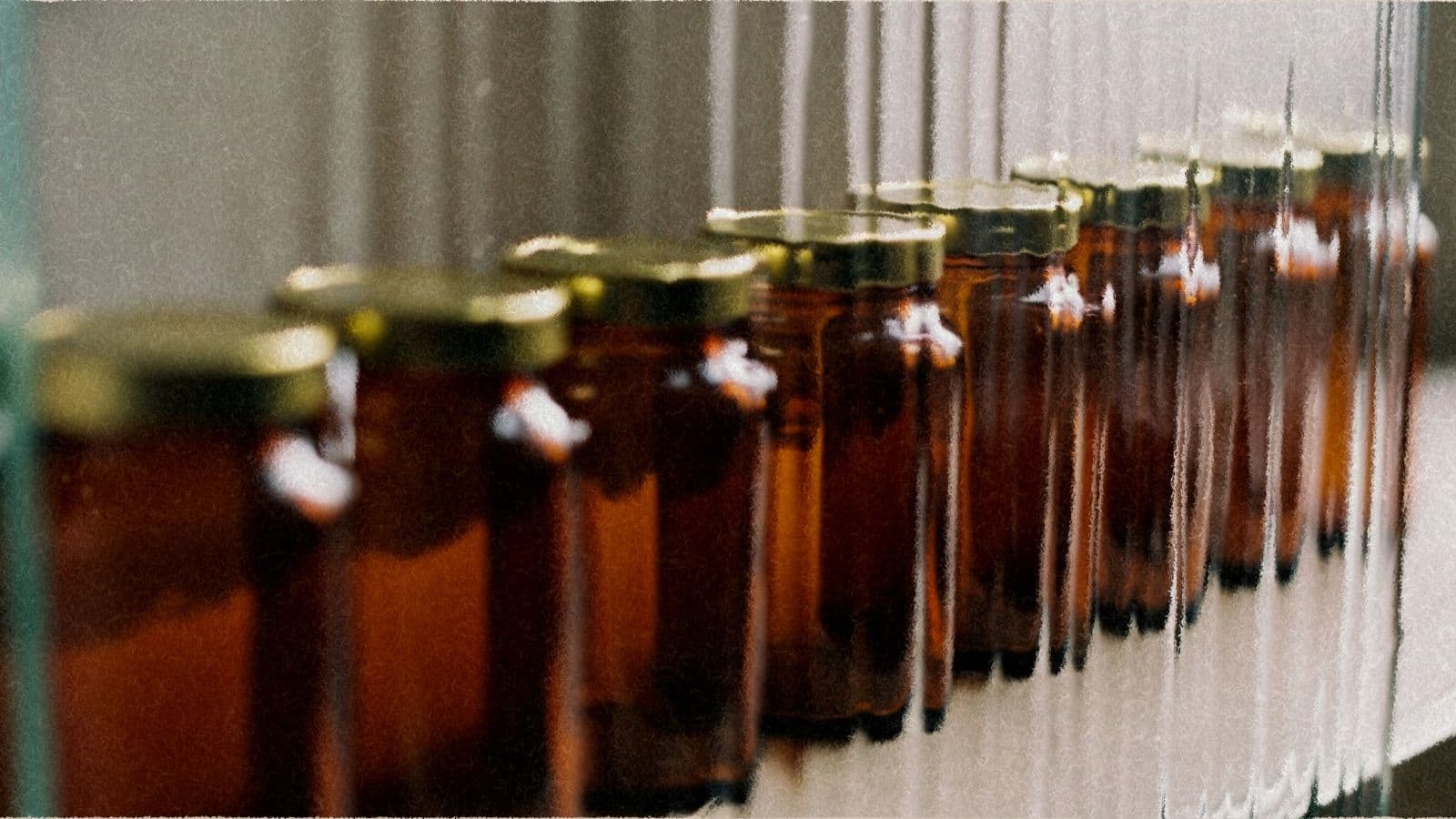 A row of amber jars seen through rippled frosted glass, one out of line.